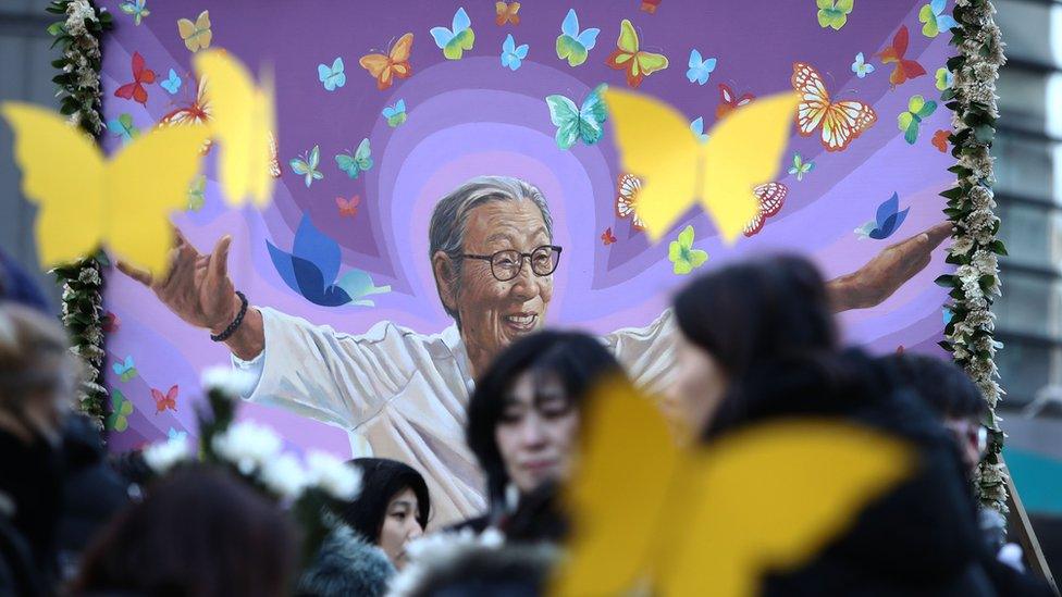 A painting of Kim Bok-dong with women carrying butterflies in front of it