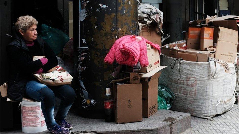 A woman sits under a poster for presidential candidates along a street in Buenos Aires