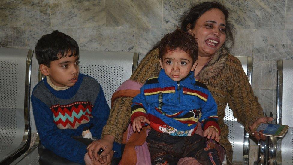 A woman cries as she sits with two young boys, one bloodstained, on a bench, following the attack in Quetta (December 17, 2017)