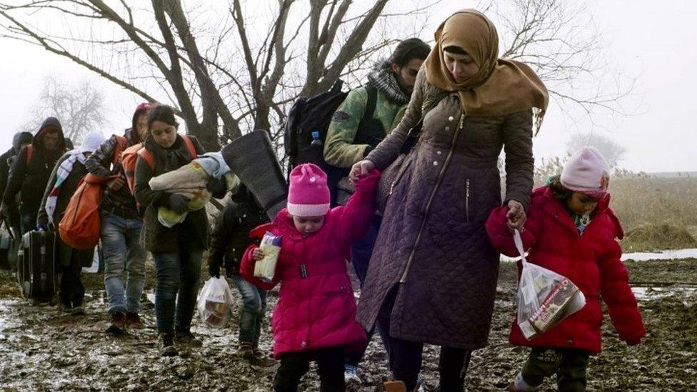 Migrants walk through thick mud as they cross the Macedonia-Serbia border in the southern Serbia (27 January 2016)