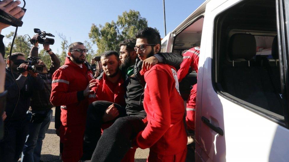 Red Crescent workers help evacuate an injured man from the Syrian city of Homs