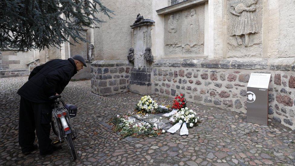 A man with a bicycle looks at a memorial plaque against anti-Semitism outside the Stadtkirche in Wittenberg, Germany (4 February 2020)