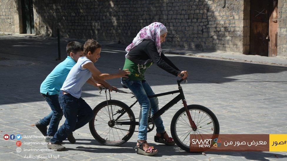 Syrian children play with a bike