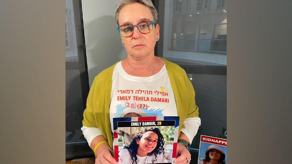 Mandy Damari holds up a photo of her daughter Emily Damari, who is being held hostage by Hamas in the Gaza Strip, during a visit to the UK (3 December 2024)