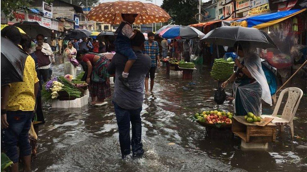 People trying to navigate the streets flooded with rain, umbrellas at hand.