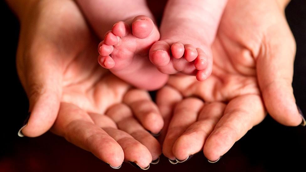 Baby's feet held in mother's hands