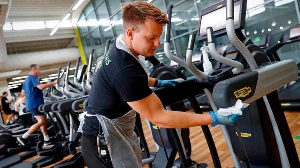 Gym staff cleaning down equipment