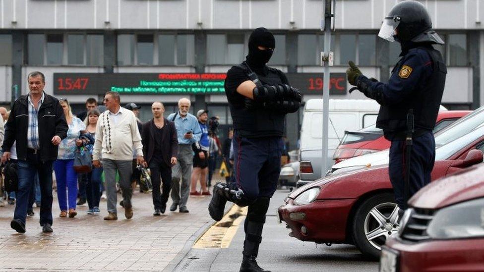 Law enforcement officers stand guard as people, including employees of Minsk Tractor Works, gather near the plant to protest against presidential election results and to demand re-election in Minsk, Belarus August 19, 2020.