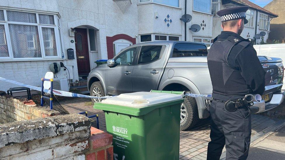 Police officer stands guard outside the house where a woman and two boys were found dead