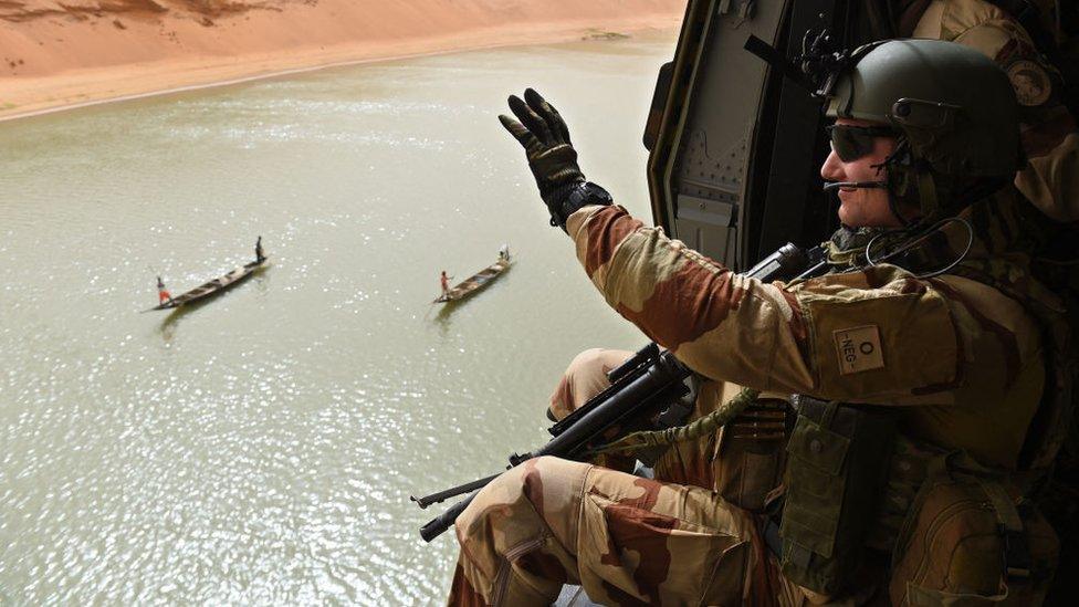 A French soldier salutes fishermen as he overflies the Niger river on the French army helicopter NH 90 "Caïman" on June 1, 2015 during the Operation Barkhane, an anti-terrorist operation in the Sahel