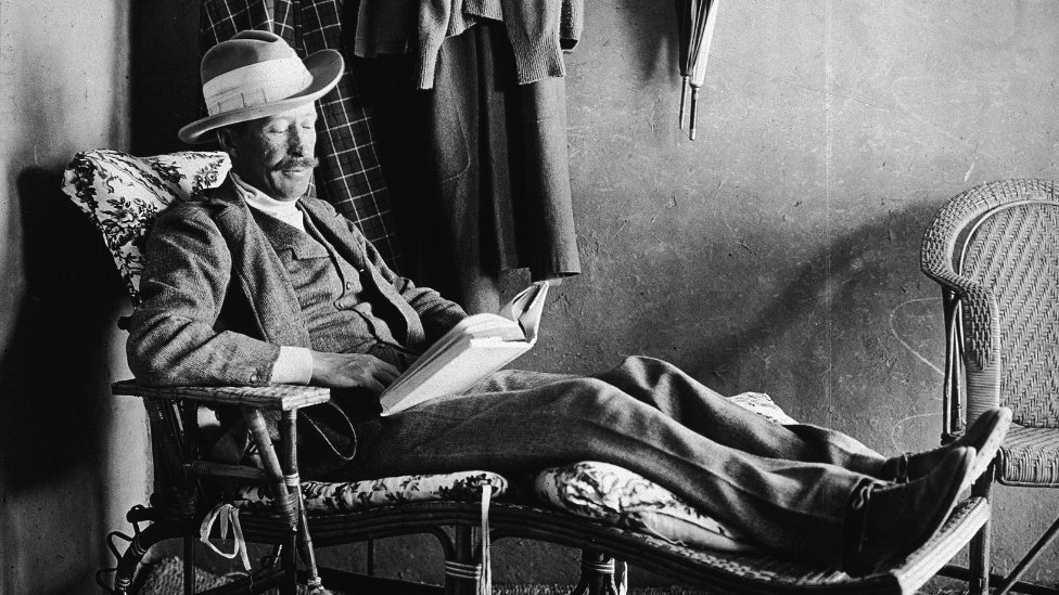 British Egyptology patron George Herbert, Fifth Earl of Carnarvon (1866 - 1923) reclines on a wooden easy chair and reads a book, Egypt, 1923.