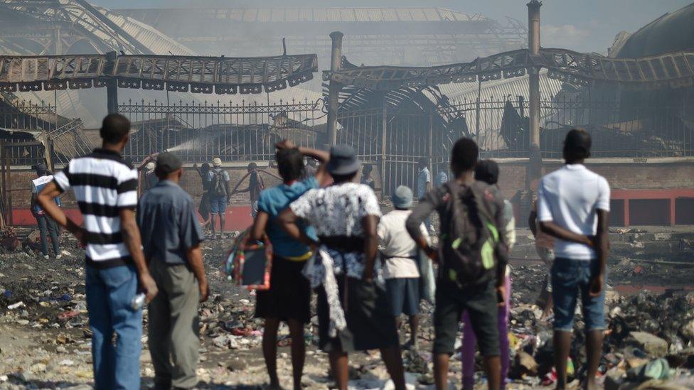 Citizens look as the burnt hull of the Iron Market.