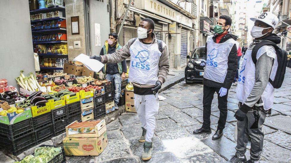 three-men-wearing-volunteer-vests-and-masks-in-a-street