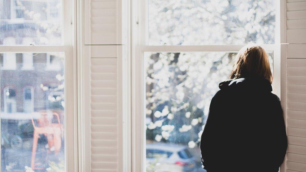 Woman standing by a window looking out