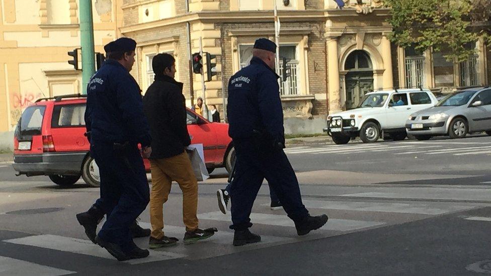 Afghan man taken away by police down busy street