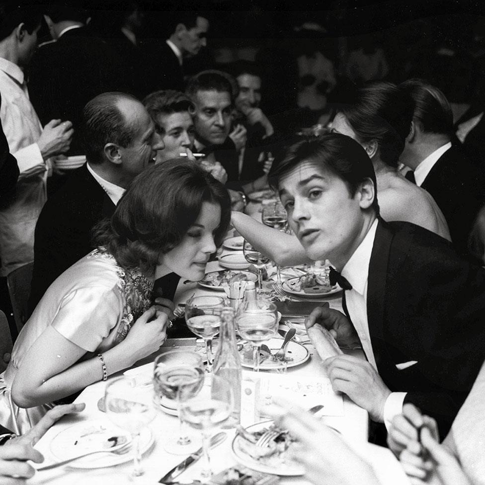 A man and woman talk to each other over a dining table