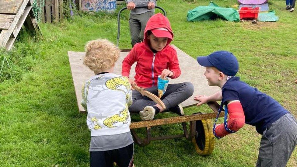 Children playing by a trolley in a garden