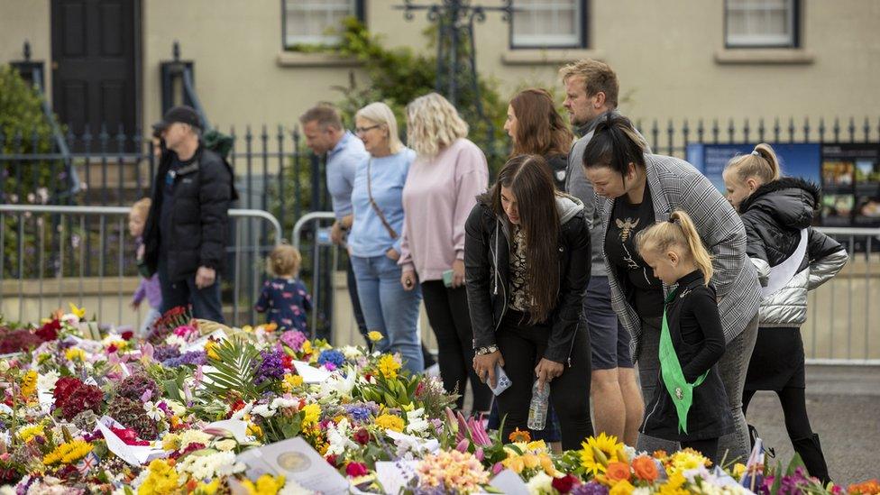 Members of the public look at flowers and wreaths left in remembrance to Queen Elizabeth II at Hillsborough Castle in Northern Ireland. Picture date: Monday