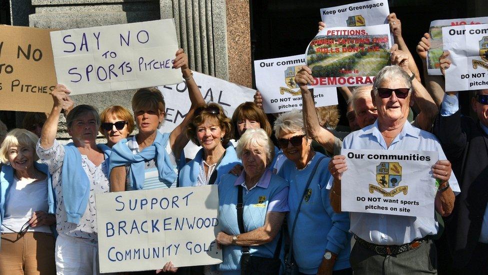 protestors hold placards outside council