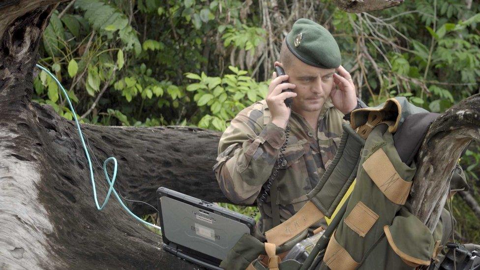 Captain Vianney uses a satellite phone to coordinate the operation from within the jungle