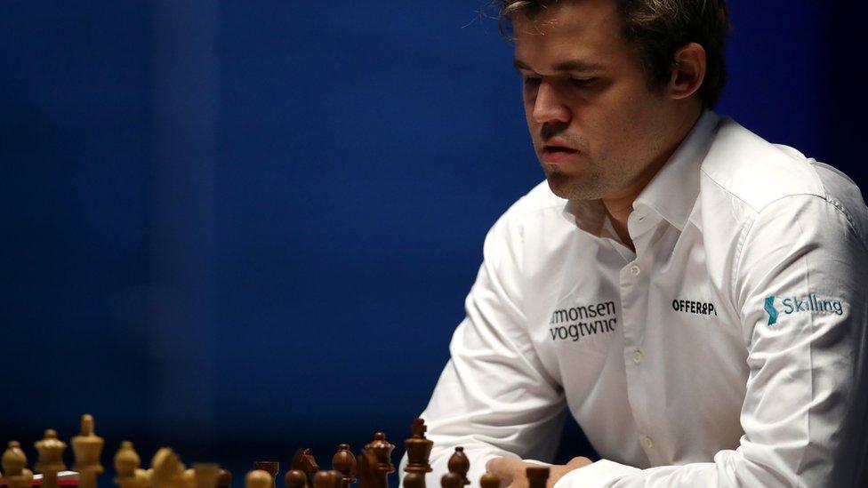 Chess player Magnus Carlsen looks down at the board during a game