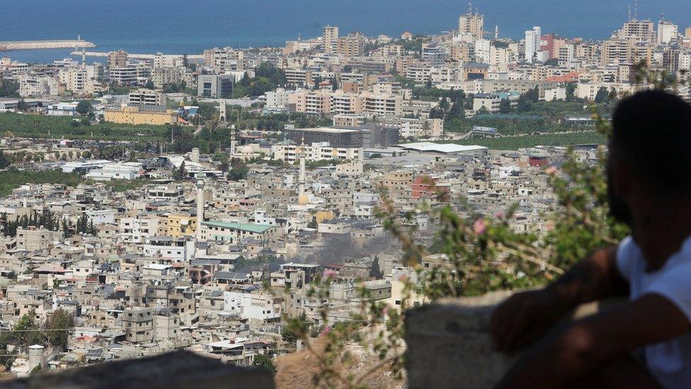 A man looks at smoke rising from Ein el-Hilweh Palestinian refugee camp during clashes between Palestinian factions on 11 September 2023