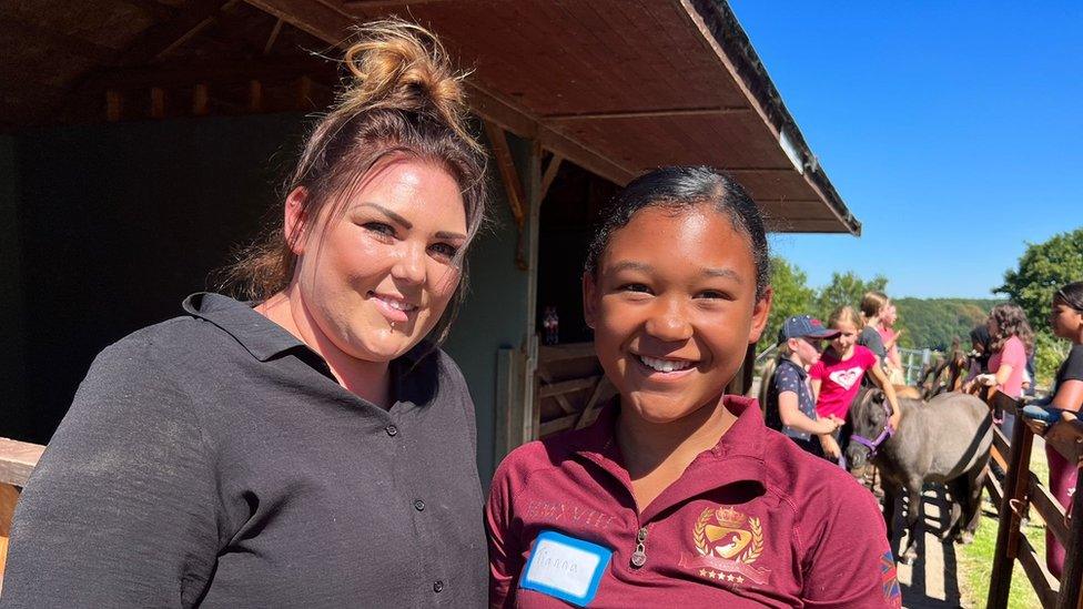 Woman and her daughter at a stable, smiling