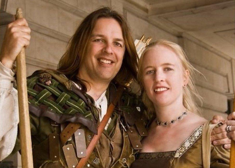 Tim Pollard and his wife Sally smiling. He holds a bow