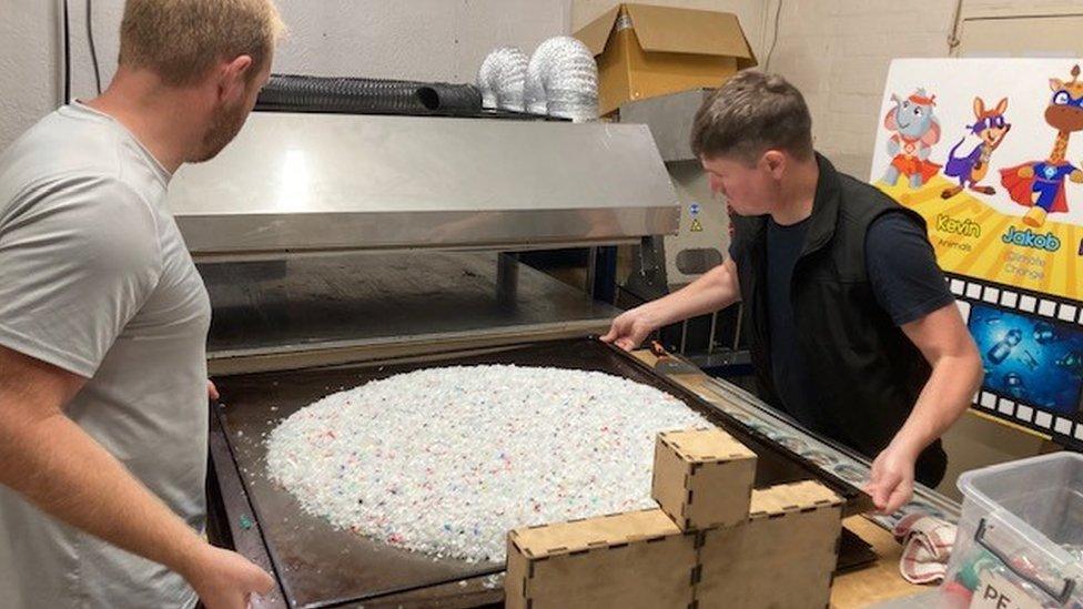 Two men with a tray of plastic fragments