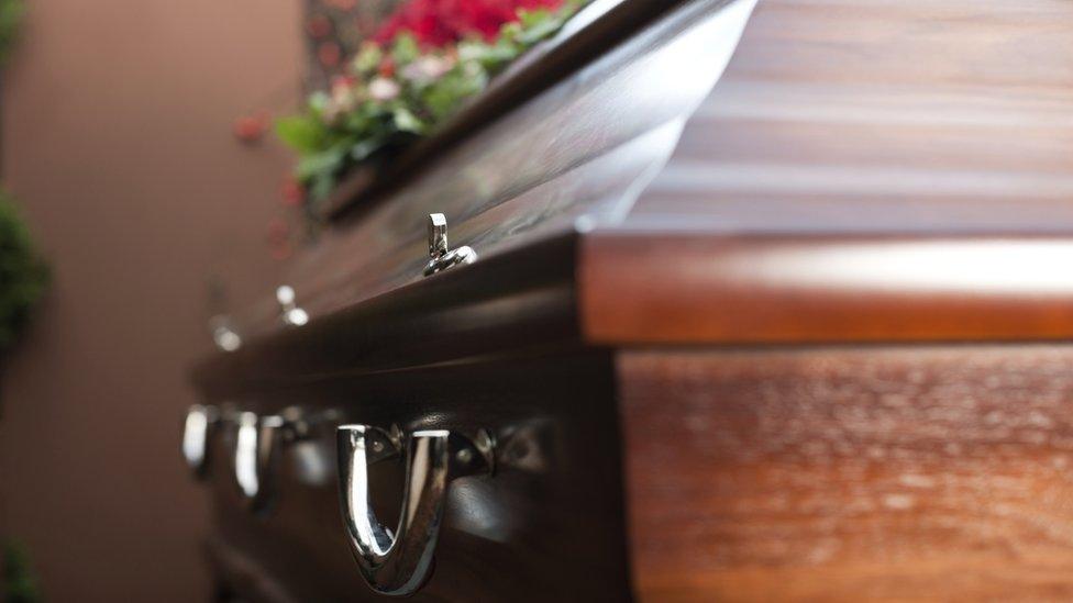 Close-up of a closed coffin and funeral flowers