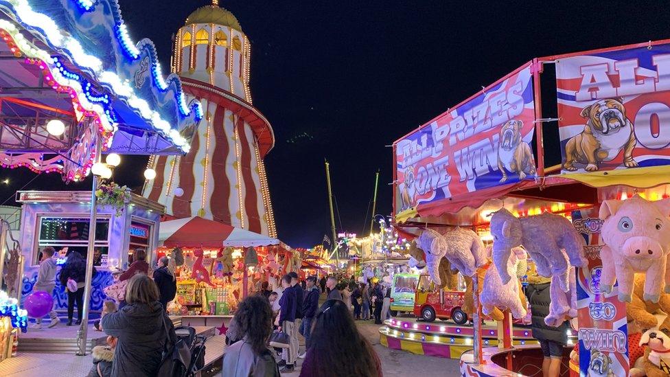 People walking past fairground rides