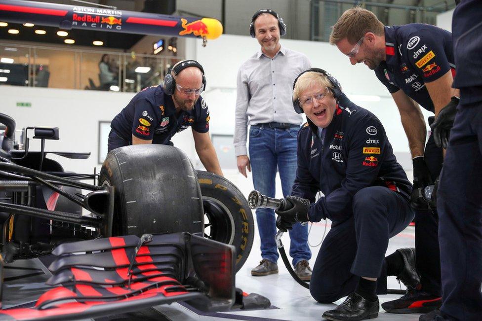 Prime Minister Boris Johnson changes a wheel on a Formula One car during a visit at Red Bull Racing in Milton Keynes