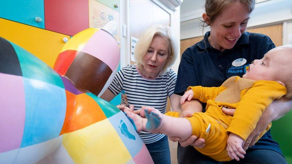 Two women and a baby painting one of the sculptures