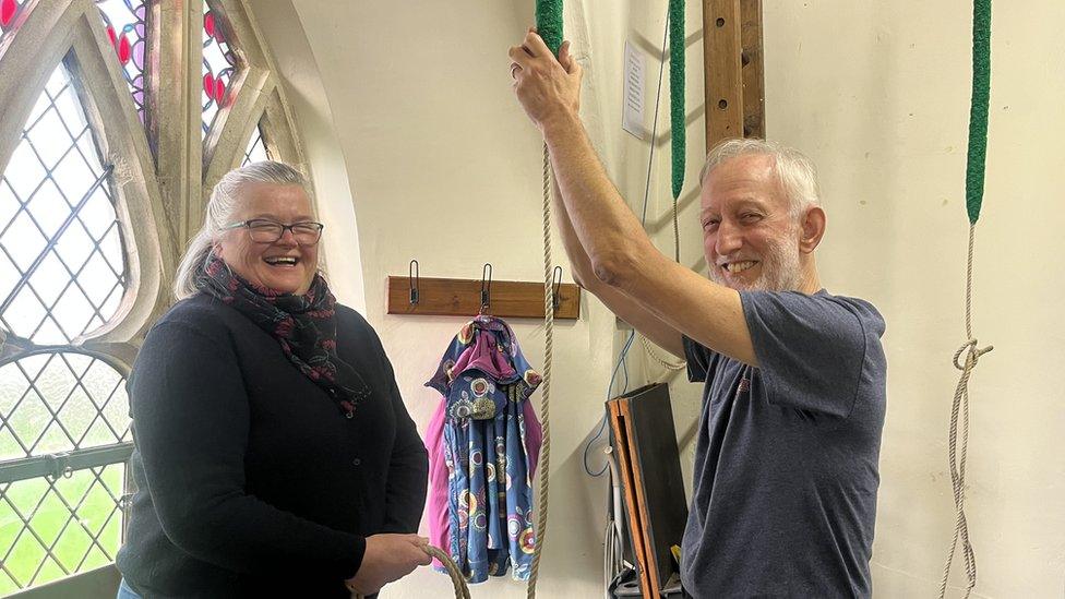 Norma and Les smiling while pulling the bell rope