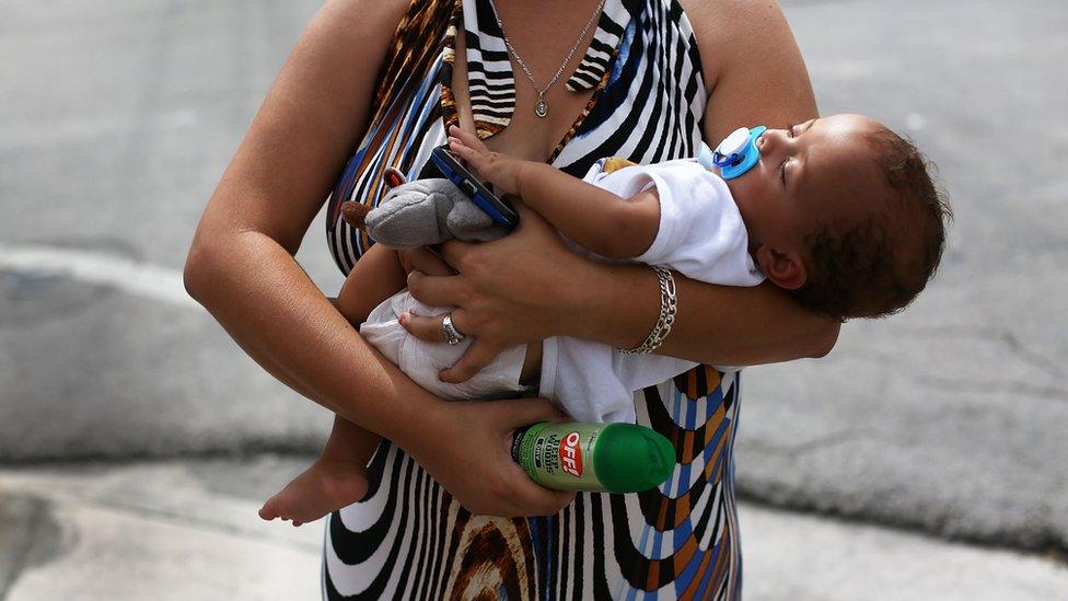 A woman holds her baby after being given a can of insect repellent in Miami, Florida