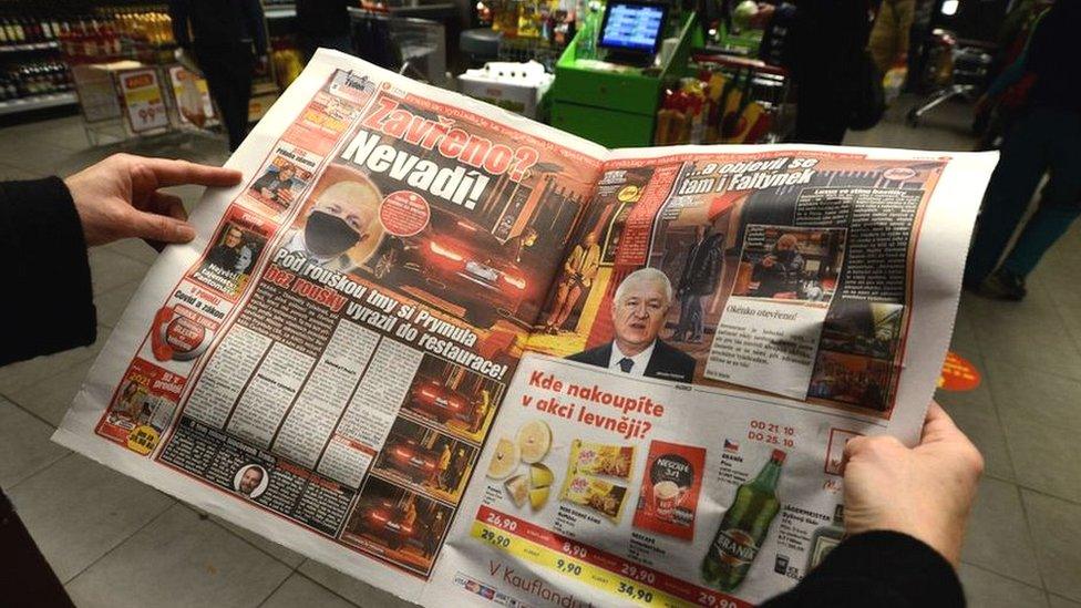 A woman reads an article in the "Blesk" Czech tabloid newspaper with images of the Minister of Health of the Czech Republic Roman Prymula allegedly dining at a restaurant despite Covid-19 restrictions in Prague, on October 23, 2020.