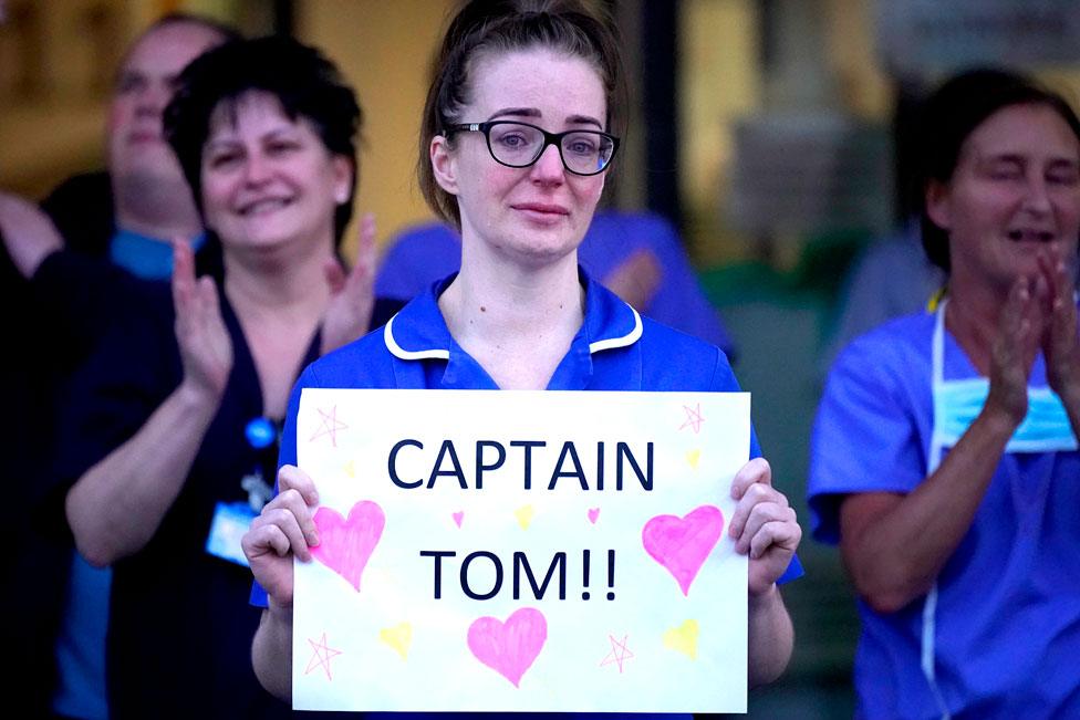 A nurse holds a sign saying "Captain Tom"