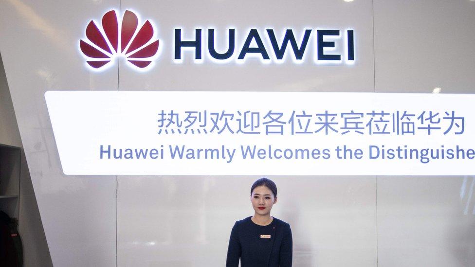 A hostess waits as journalists arrive for a press conference and launch of new 5G Huawei products at the Huawei Beijing Executive Briefing Centre