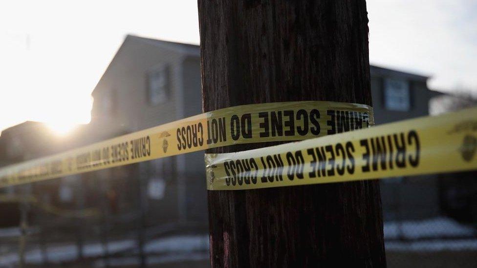 A house with a tree in the foreground with police tape