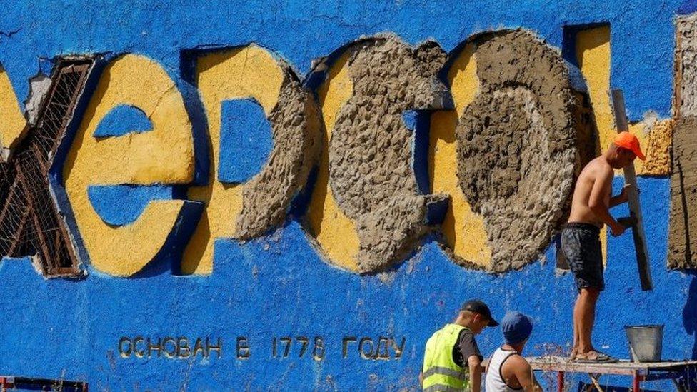 Workers remove the bas-relief that reads "Kherson" of a damaged monument in Kherson, southern Ukraine. Photo: July 2022