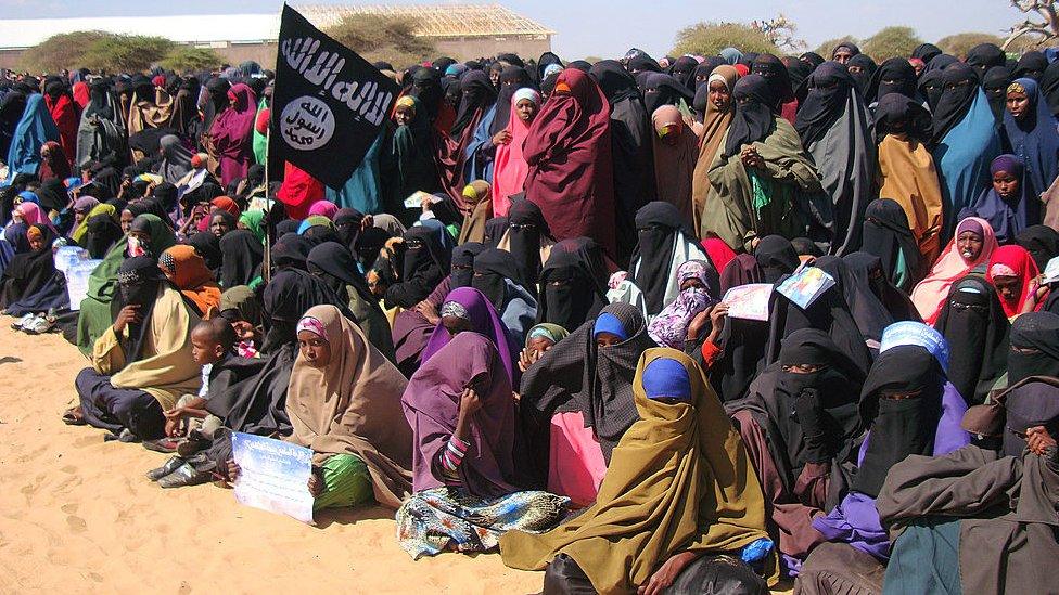 Women look at al-Shabab fighters following a demonstration