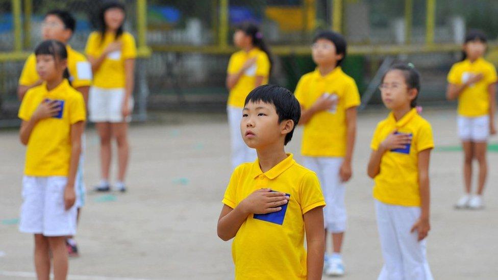 South Korean schoolchildren stand to attention during their national anthem