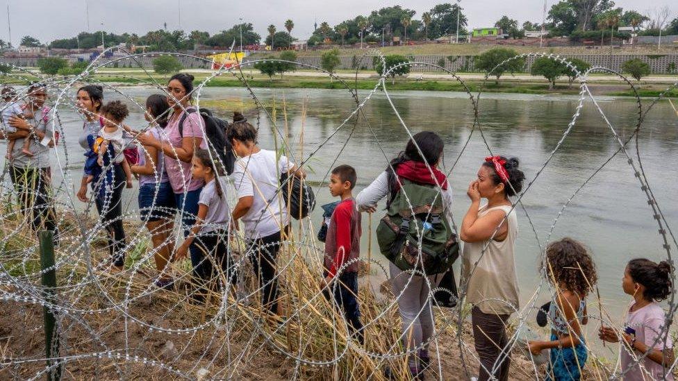 People seeking asylum speak with law enforcement after illegally crossing the Rio Grande into the United States on June 14, 2023 in Eagle Pass, Texas.