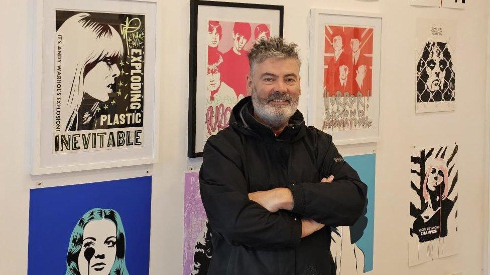 Artist Pure Evil standing in front of his new exhibition