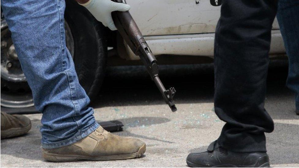 Police officers inspect an AK47 assault rifle found in a taxi with a dead woman inside, after a shooting involving police, in Acapulco, Guerrero State, Mexico on July 26, 2016