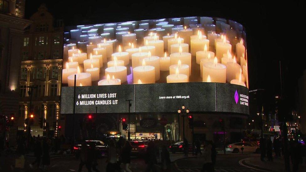 Candles are projected on a screen in Piccadilly Circus