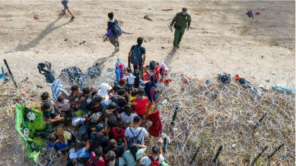 A US border guard observes migrants entering the US