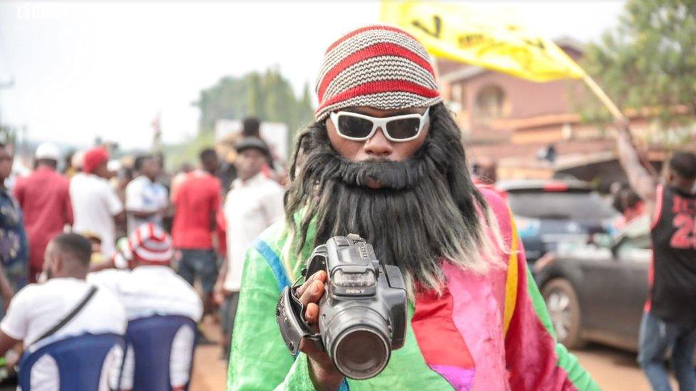 A man in a fake beard and video camera in Arondizuogu during the Ikeji Festival in Nigeria