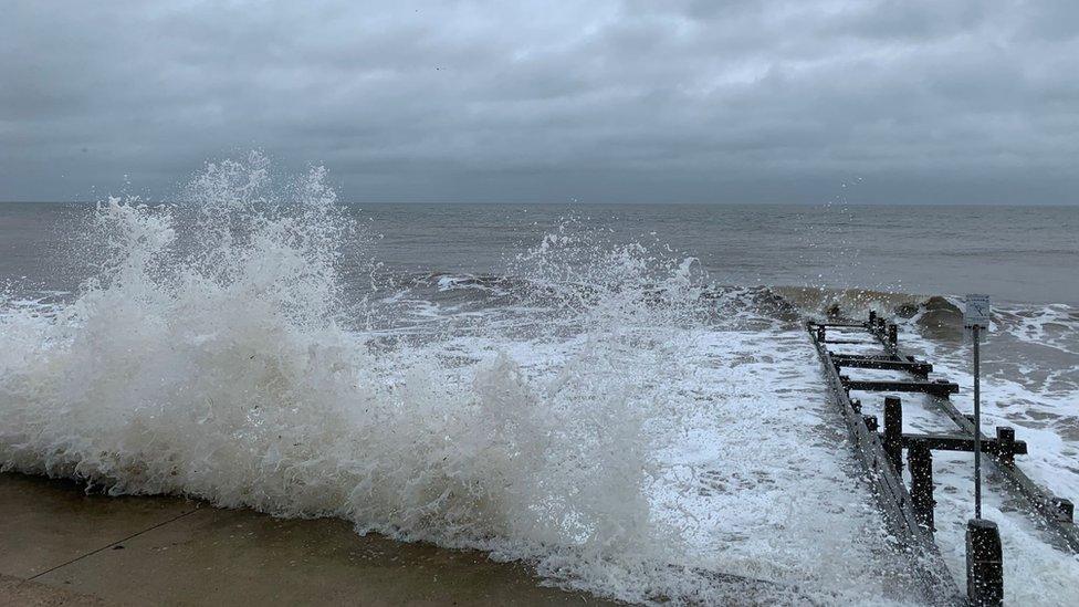 Waves crash over the coast road at Walcott, Norfolk