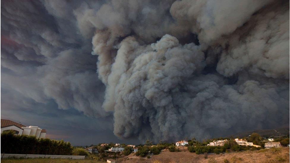 A massive smoke plume, powered by strong winds, rises above the the Woolsey Fire